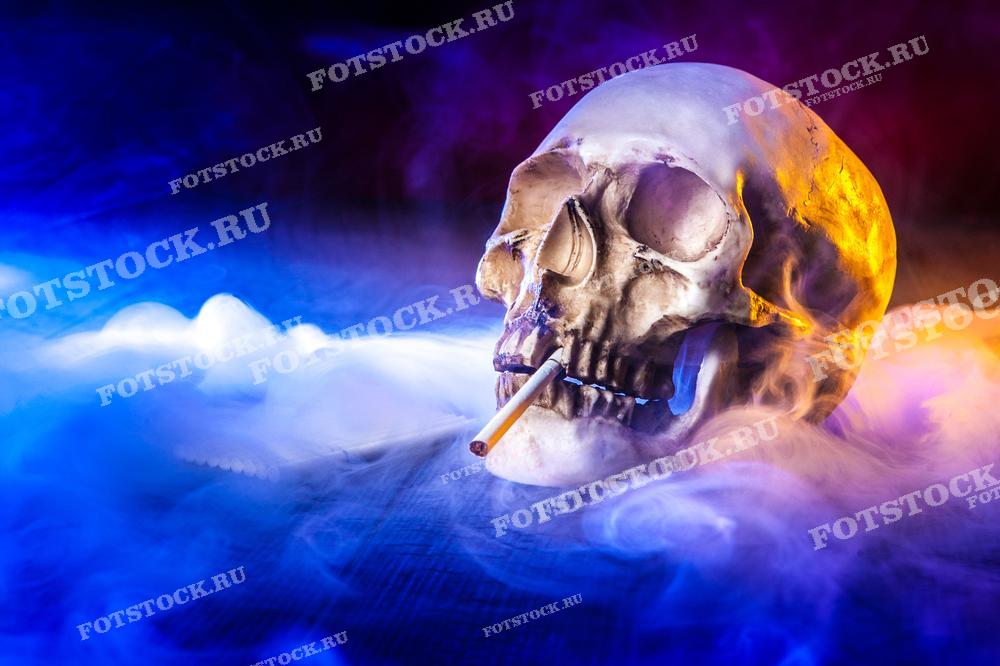 На фотографии изображен череп с сигаретой, окруженный густым дымом в яркой цветовой гамме. Снимок символизирует опасность курения и его связь со смертью.